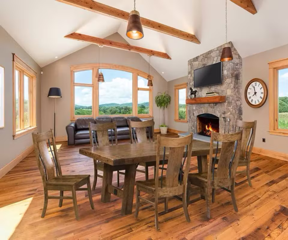 Rustic Amish dining room with exposed beams, stone fireplace, and barn wood table